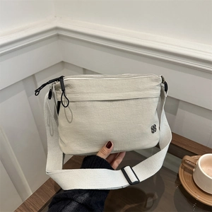 Minimalist off-white nylon crossbody bag with three zippers and wide shoulder strap