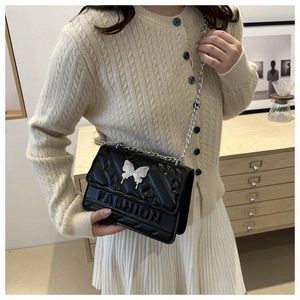 Détail du sac bandoulière noir matelassé avec fermoir papillon et bandoulière chaîne