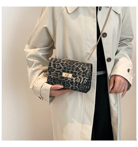 Close-up of leopard print crossbody bag with gold chain strap on a beige trench coat