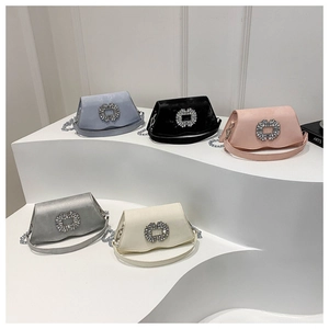 Detail view of five satin square handbags with rhinestone buckles on a white stand