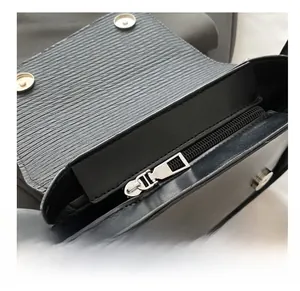 Macro view of black epi leather shoulder bag showing silver zipper and magnetic buckle
