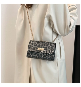 Detail of leopard print crossbody bag with gold chain strap on stylish trench coat