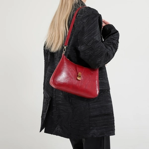 Sac croissant rouge vintage avec boucle dorée sur un manteau noir texturé