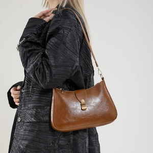 Sac croissant marron vintage en cuir huilé porté à l'épaule par un mannequin