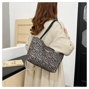 Close-up of leopard print canvas tote bag with black shoulder straps and gold nameplate
