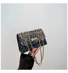 Detail view of leopard print crossbody bag with gold chain strap and metal turn-lock