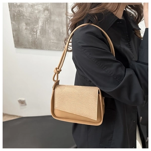 Detail showing the brown shoulder bag with ribbed textured flap and knotted strap detail