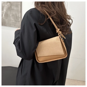 Detail view of khaki shoulder bag with wave texture flap and metal strap buckle