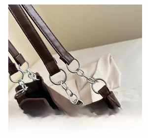 Detail of suede tote bag showing silver metal ring chain and leather shoulder strap
