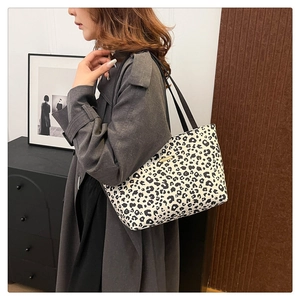 Detail of leopard print tote bag with gold logo plate and slim black shoulder straps