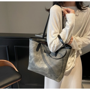 Close-up of grey washed canvas tote bag with black leather trim and shoulder strap