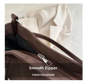 Detail showing the smooth silver metal zipper and dark brown suede fabric texture