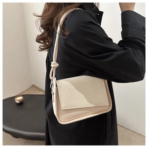 Detail of cream PU leather shoulder bag with textured stripes and decorative knot strap