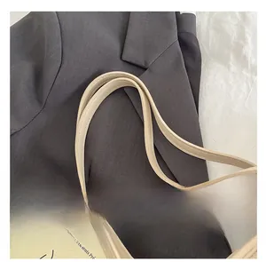 Detailaufnahme der breiten Schultergurte einer hellbeigen Ledertasche für modebewusste Damen