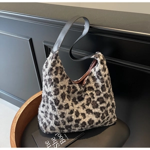 Close-up of fluffy faux fur leopard print tote bag with black leather shoulder strap