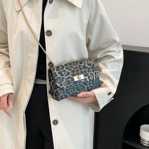 Fashionable leopard print flap crossbody bag with gold chain strap on beige trench coat