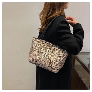 Detailed view of leopard print tote bag with black straps and gold logo on a model