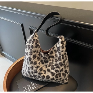 Close-up of plush leopard print faux fur texture and black leather strap on hobo bag