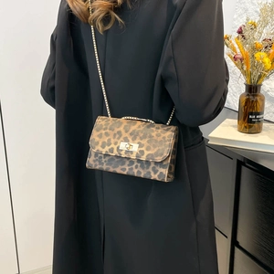 Fashionable leopard print small square chain bag for women worn over a black trench coat