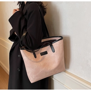 Detail of a large pink tote bag with black leather trim and contrasting shoulder handles