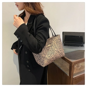 Detail of leopard print tote bag with gold logo plaque and black shoulder straps