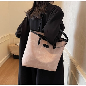 Close-up of pink marble pattern tote bag with black trim on a model's shoulder