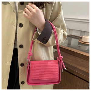 Close-up of bright pink shoulder bag featuring wave textures and knotted rope strap details