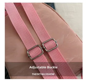 Detailed view of pink backpack with adjustable shoulder strap and silver metal buckle