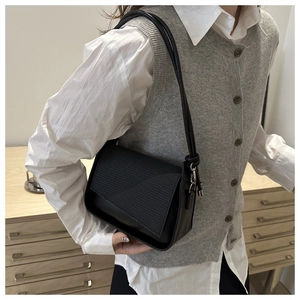 Detail of black textured crossbody bag showing the matte leather and metal buckle adjustment
