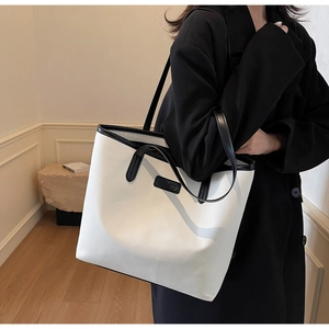 Detail showing high-quality black and white leather tote bag with branded patch and trim