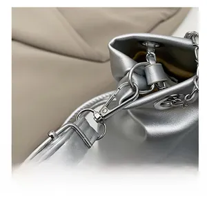 Detailed macro view of silver metallic swivel hook and chain strap on a bucket bag