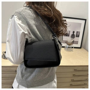 Detail of black water ripple textured shoulder bag with silver metallic hardware and adjustable strap