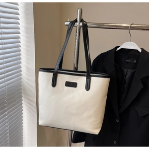 Detailed close-up of a minimalist cream tote bag hanging on a rack in an office setting
