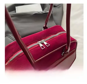 Close-up of smooth double silver zippers on dark burgundy suede and leather handbag