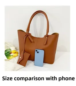 Large brown tote bag detail showing size comparison with smartphones on white surface