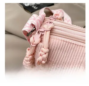Detail view of pink corduroy fabric with multiple smooth zippers and woven shoulder strap