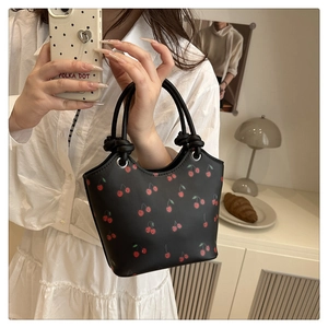 Detail of cherry print tote bag with soft knotted handles and metallic ring accents
