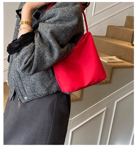 Close-up of vibrant red nylon tote bag with embossed logo showing shoulder strap detail