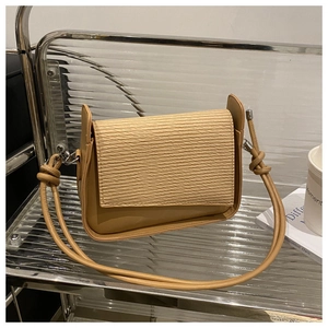 Detail of khaki crossbody bag with woven texture flap and knotted shoulder strap