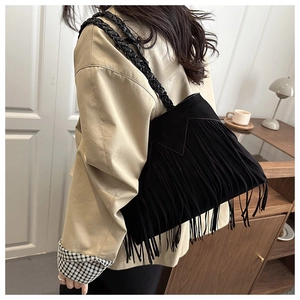 Detail of bohemian black suede bucket bag with long tassels and hand-woven handles