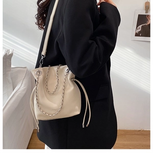 Detail of off-white bucket bag with silver chain strap and leather drawstring closure
