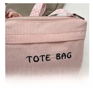 Detail of pink corduroy tote bag with TOTE BAG embroidery and geometric strap