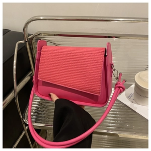 Detail of rose red crossbody bag featuring horizontal texture and thick round handle