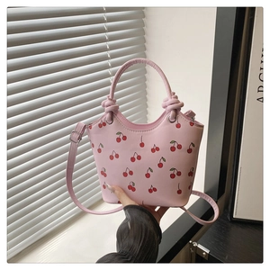 Close-up of pink tote bag with red cherry print and decorative knot handle detail