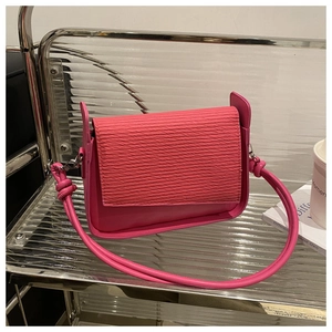 Detail of rose pink crossbody bag showing pleated flap texture and knot strap design