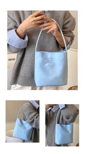 Detail of light blue tote bag featuring embossed 'Hope and future' text and slim handles