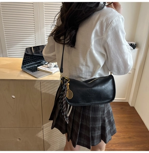 Detail of black pebbled leather half-moon shoulder bag with tennis racket and silk scarf charm