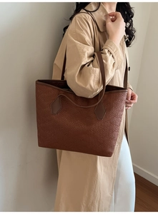 Nahaufnahme der retro dunkelbraunen Tragetasche mit Krokodilprägung auf beigem Trenchcoat