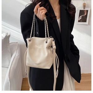 Detail of white PU leather bucket bag with elegant chain handles and adjustable strap