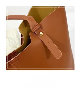 Detail view of brown tote bag featuring gold stud accents and reinforced stitching